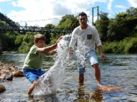 Picture of a boy standing in a stream splashing the water.