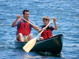 Picture of a man and a boy paddling a canoe.