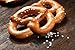 Produktbild Alu-Dibond-Bild 140 x 90 cm: "Fresh pretzels with sea salt close-up on dark board background", Bild auf Alu-Dibond
